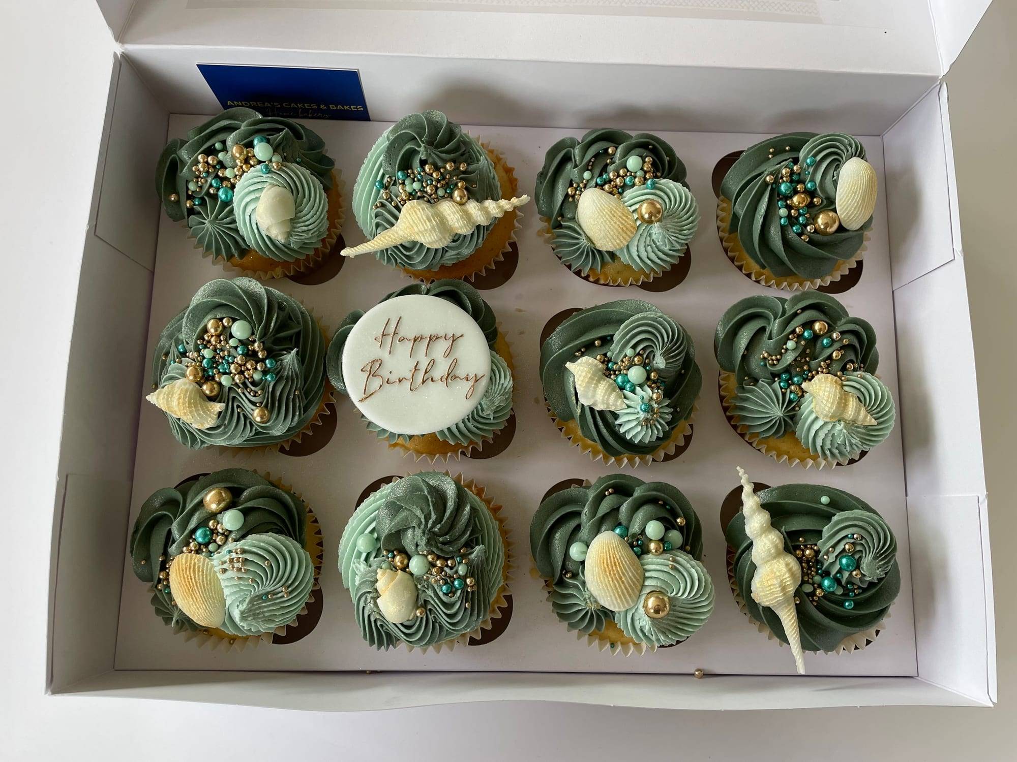 Beach-themed cupcakes with sage green swirled buttercream and white sugar seashells